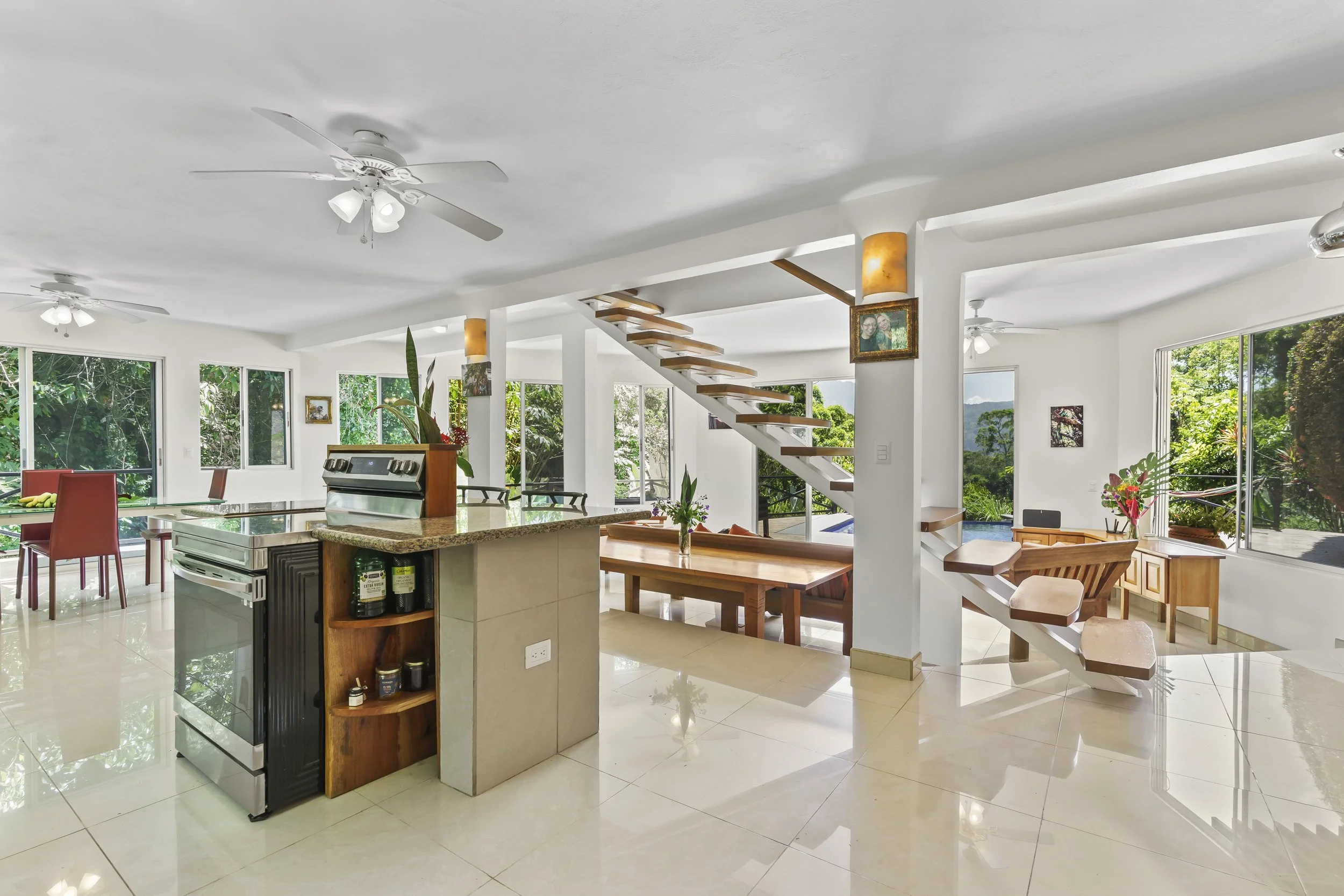 Kitchen island and open living room layout designed for gathering and entertaining.  The island is "hot" with a flat electric range and convection oven and air-fry and dehydrate features. Additional shelves on either side of the cooking area make you