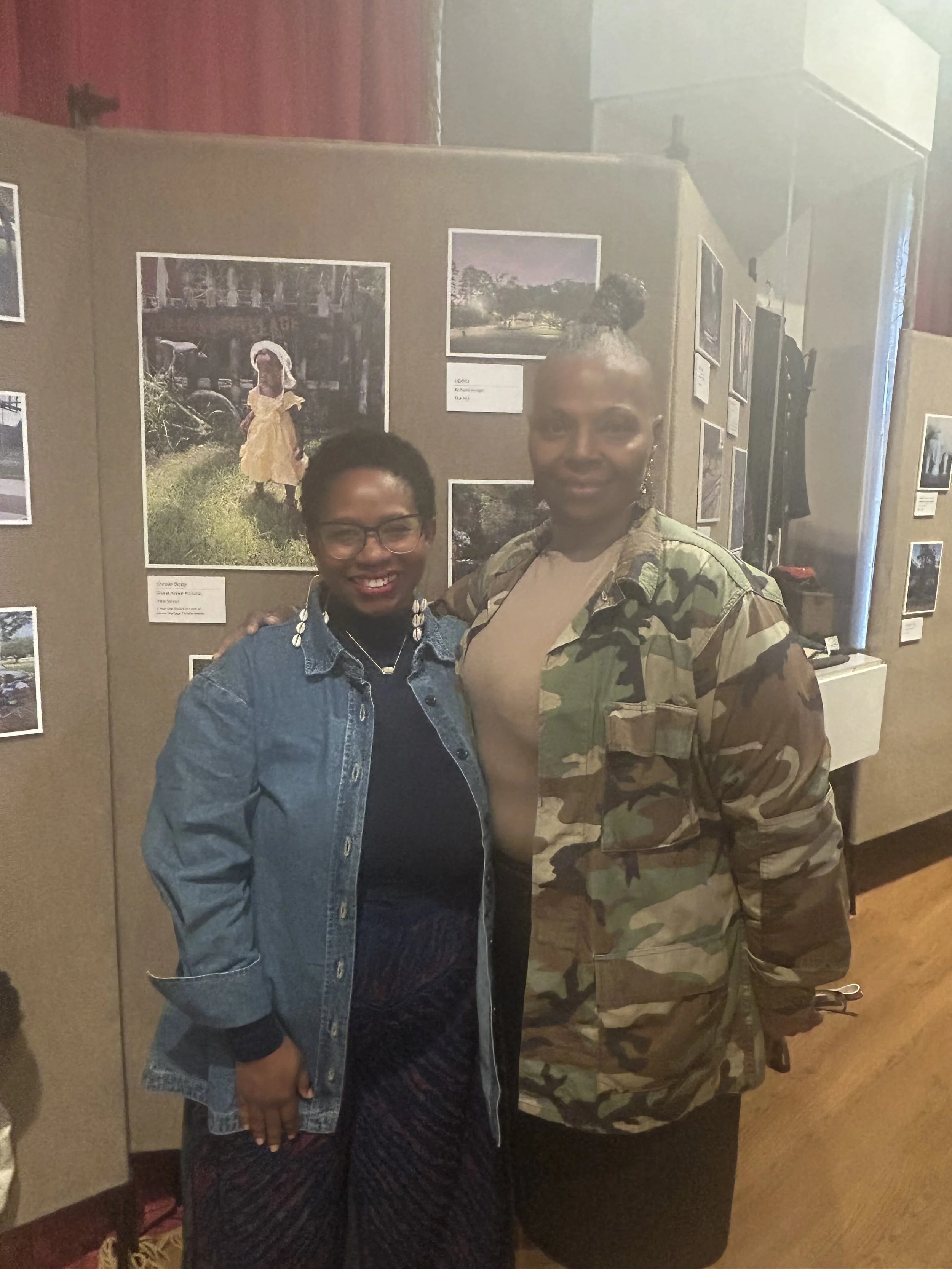 Devin (Divine) Bailey-Nicholas standing next to Elder Charlotte Marie Shilo-Goudeau with their arms around each others backs, smiling at the camera.