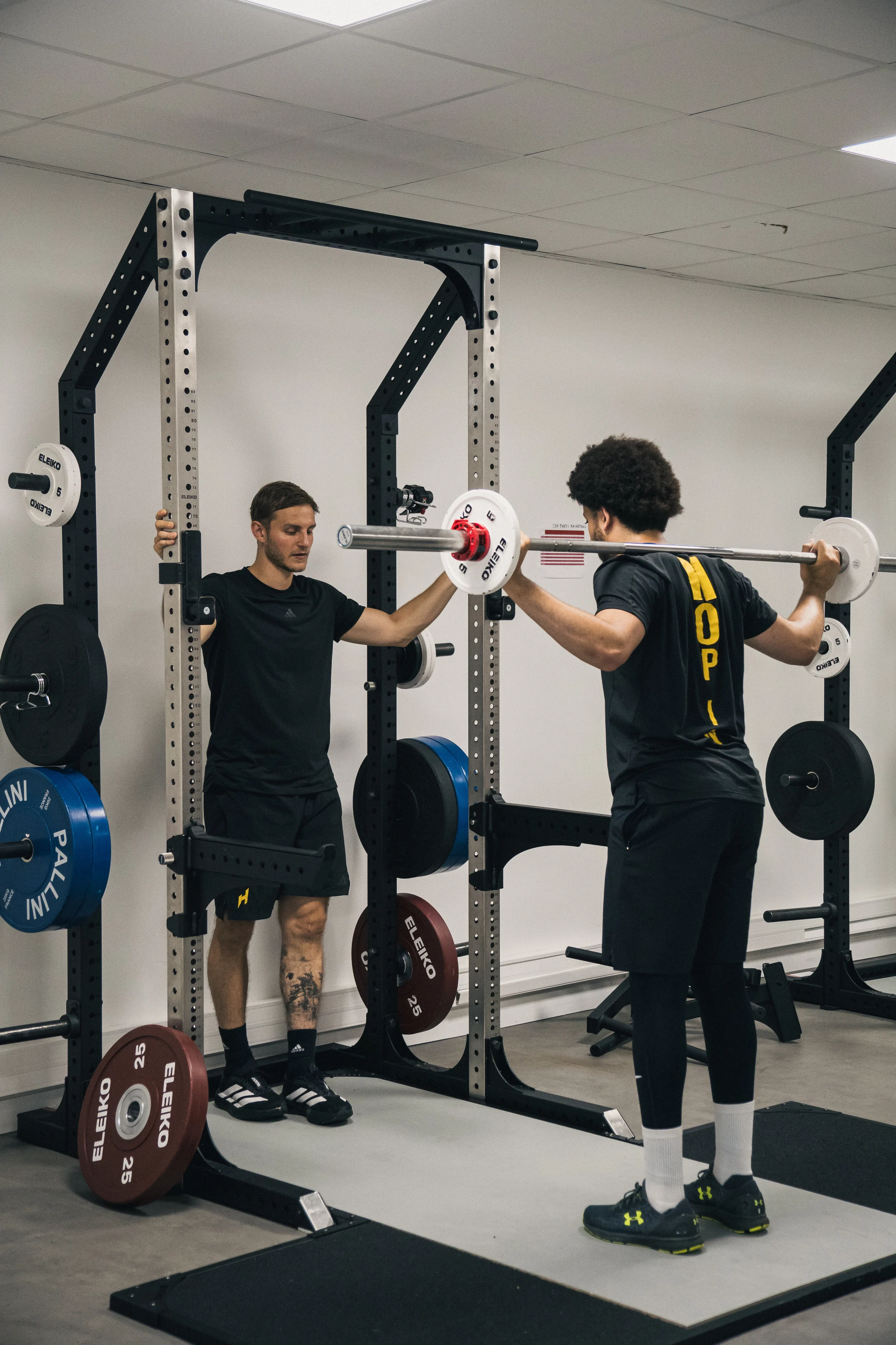 Coaching en salle : squat à la barre sous la surveillance du coach