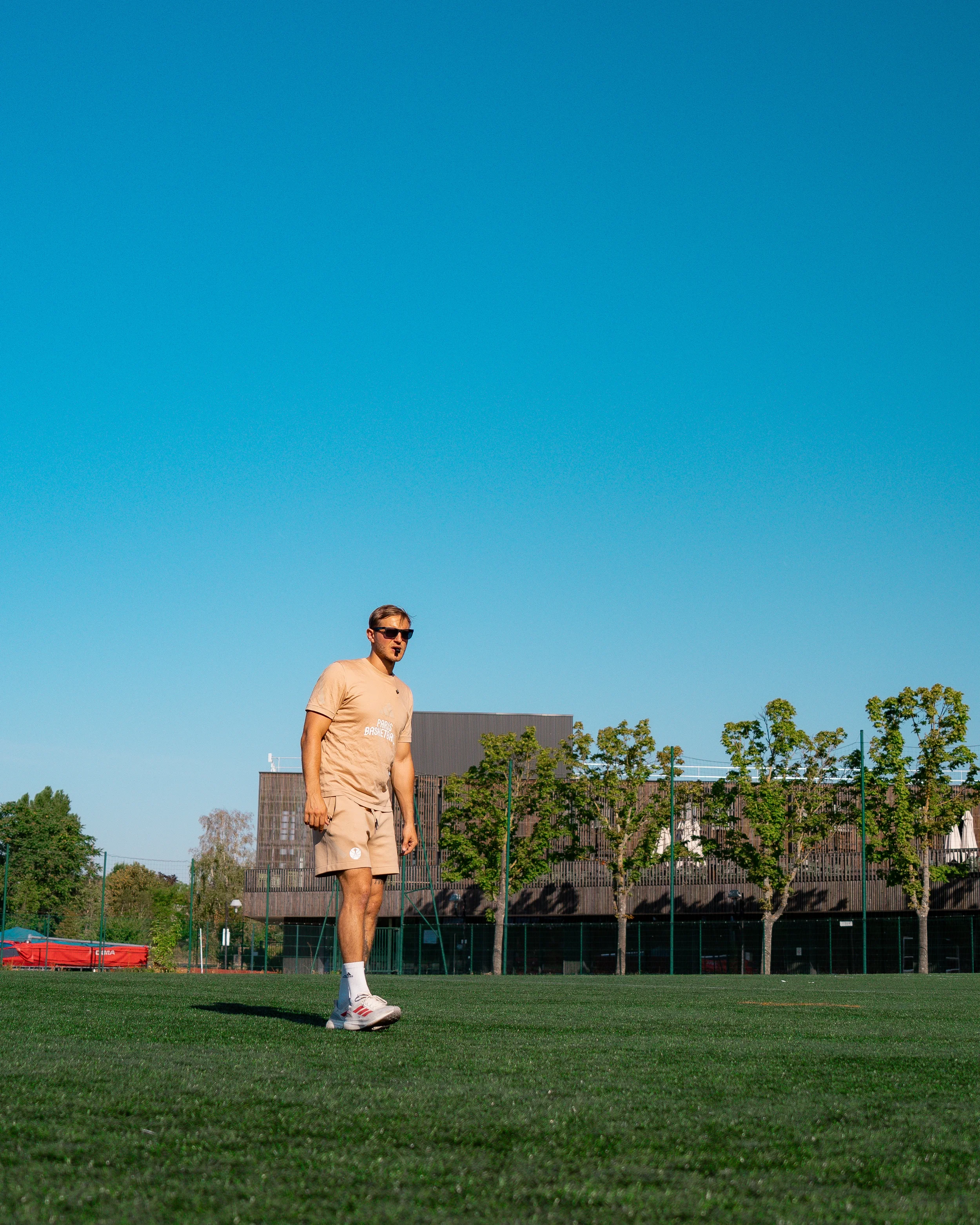 Le coach marche sur un terrain de sport sous un ciel bleu