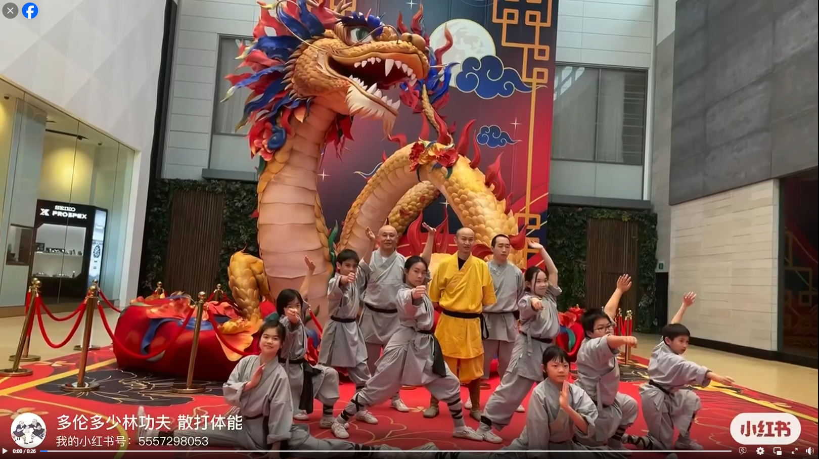 People in martial arts uniforms posing in front of a large decorative dragon statue at an indoor event.