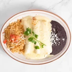 Plate of Mexican food with tamales, rice, black beans, and garnished with cilantro.