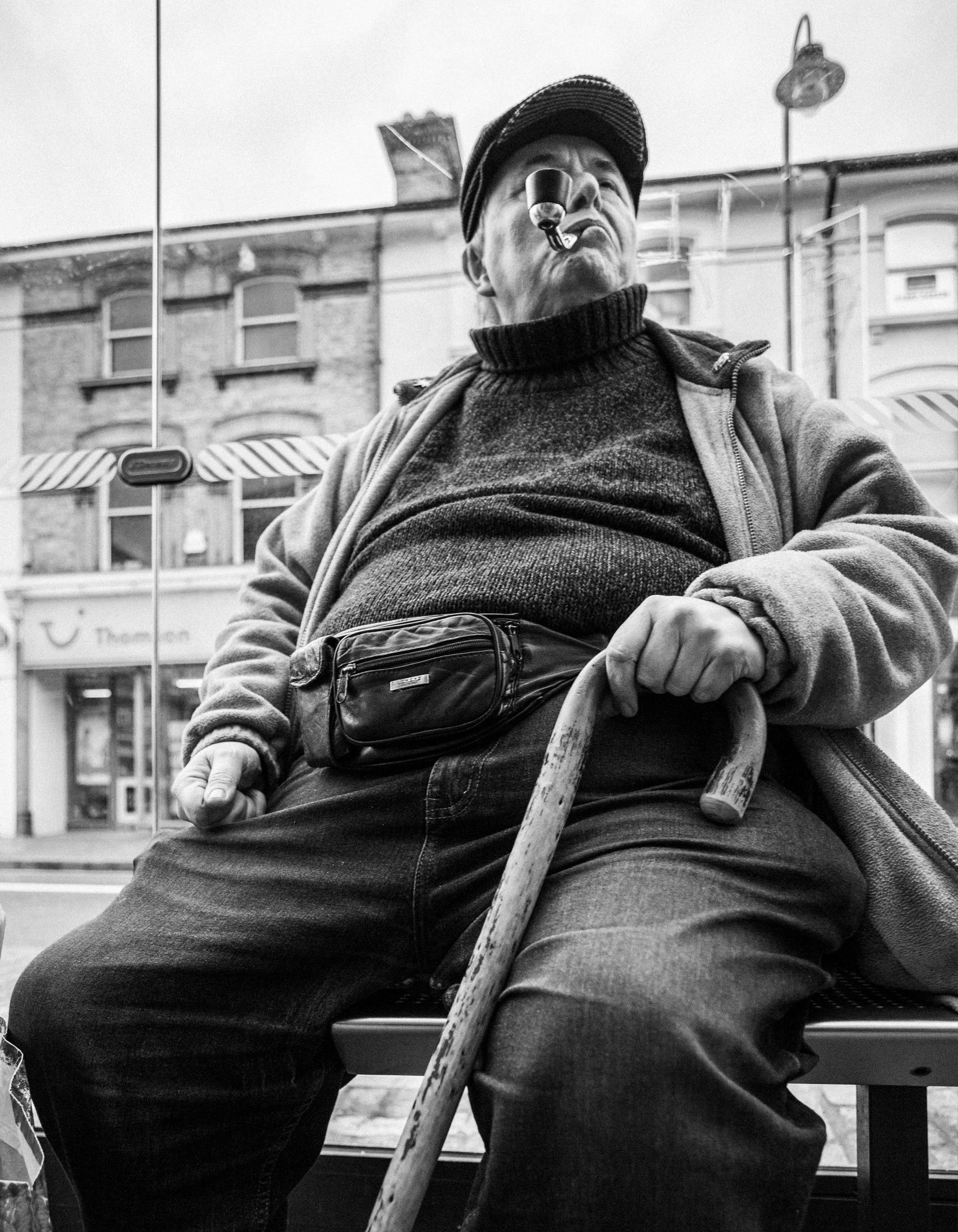 Man and his pipe waiting at a bus stop in Royal Tunbridge Wells, Kent