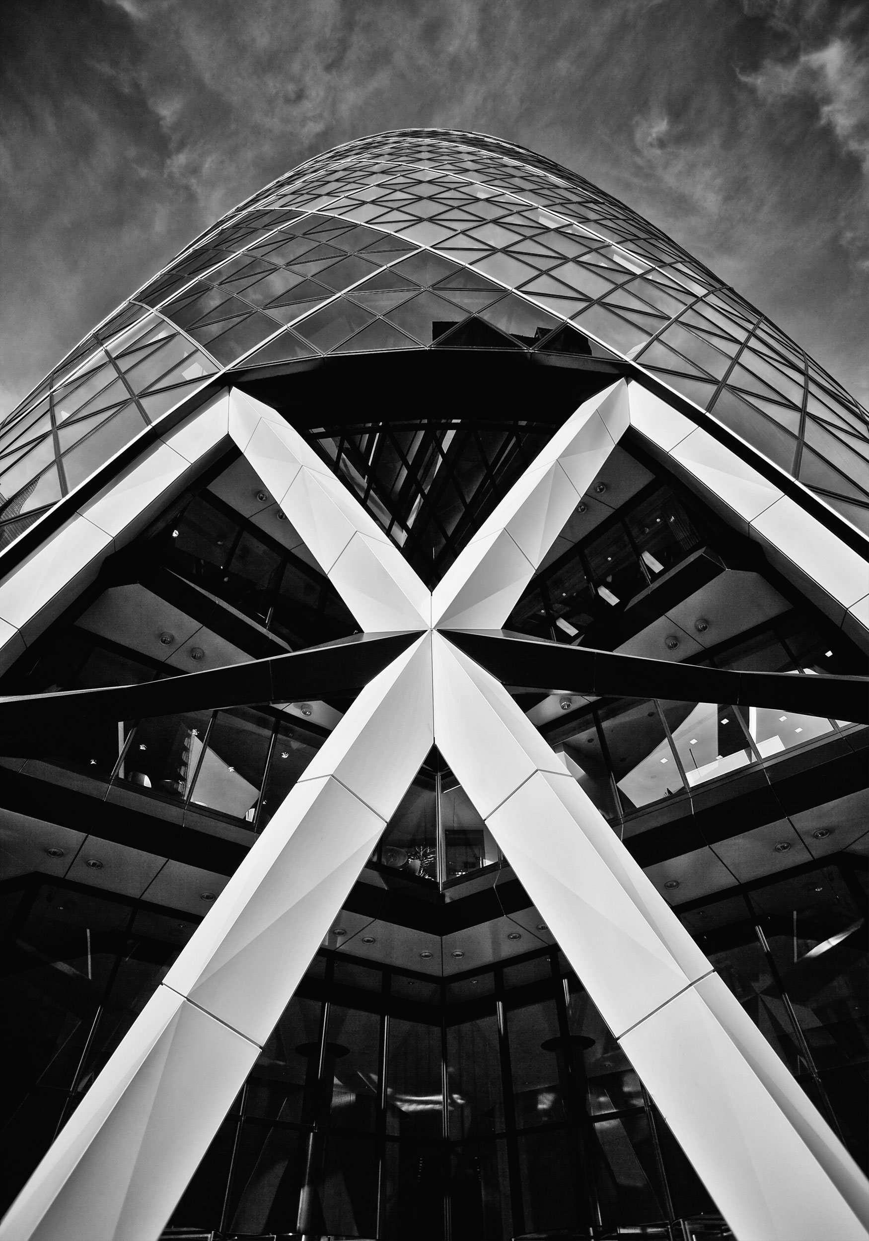 Black and white photo of a modern glass and steel skyscraper taken from ground level, looking up at the building.