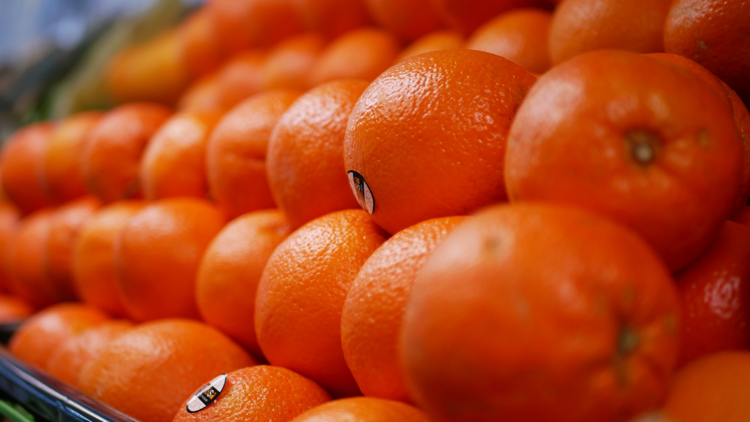 Close-up of a pile of oranges with some stickers on them.