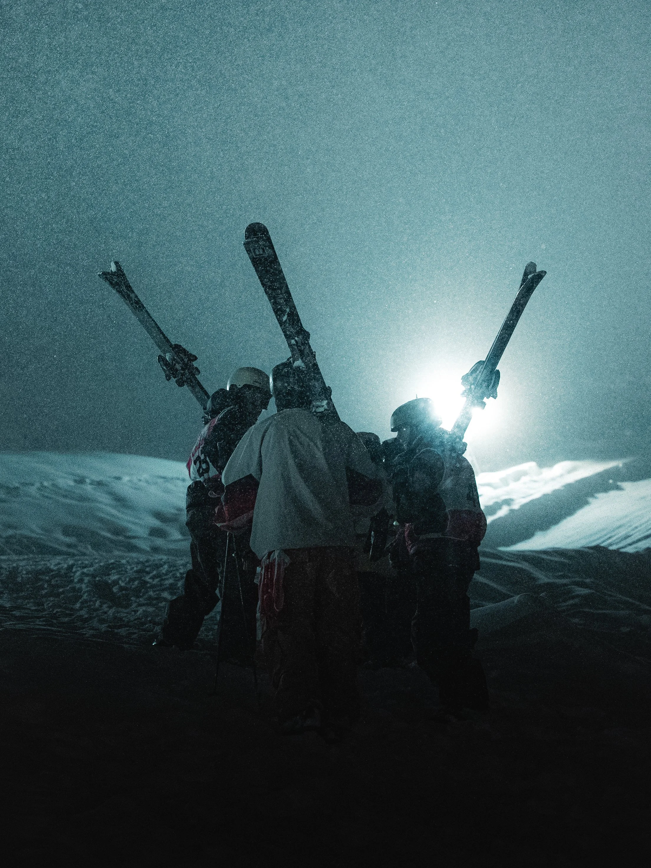 Big Air Ski contestants discussing the slope at the Whitestyle Open Murren at night under the lights in heavy snowfall