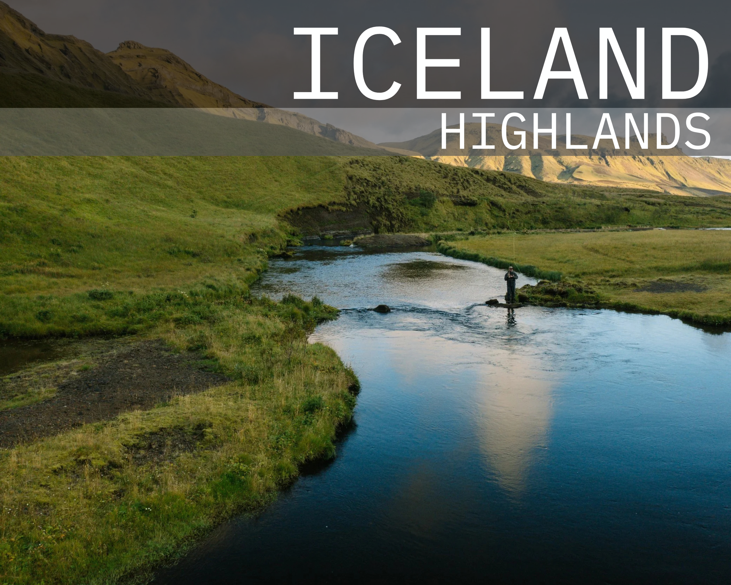 Scenic view of the Iceland Highlands with a river, black volcanic sands, green hills, and mountains in the background, and a person fishing in the river.