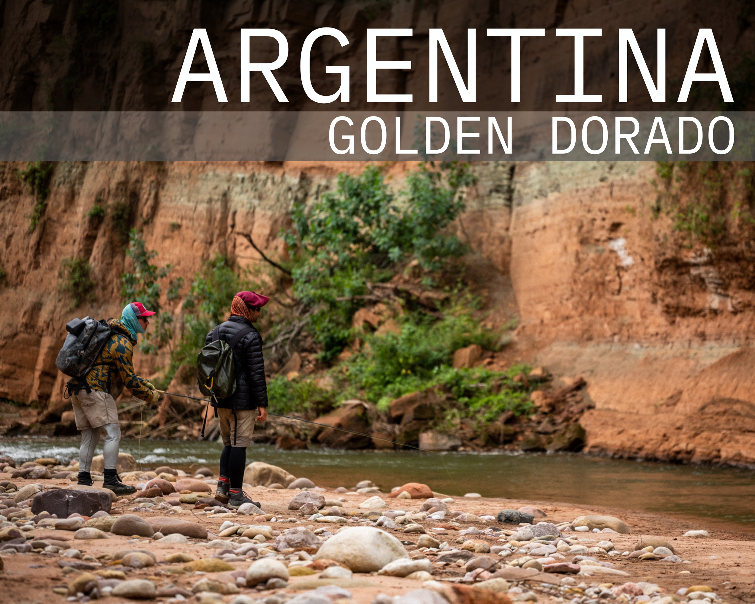 Two hikers fishing by a rocky river bed with cliffs and greenery in Argentina's Golden Dorado region.