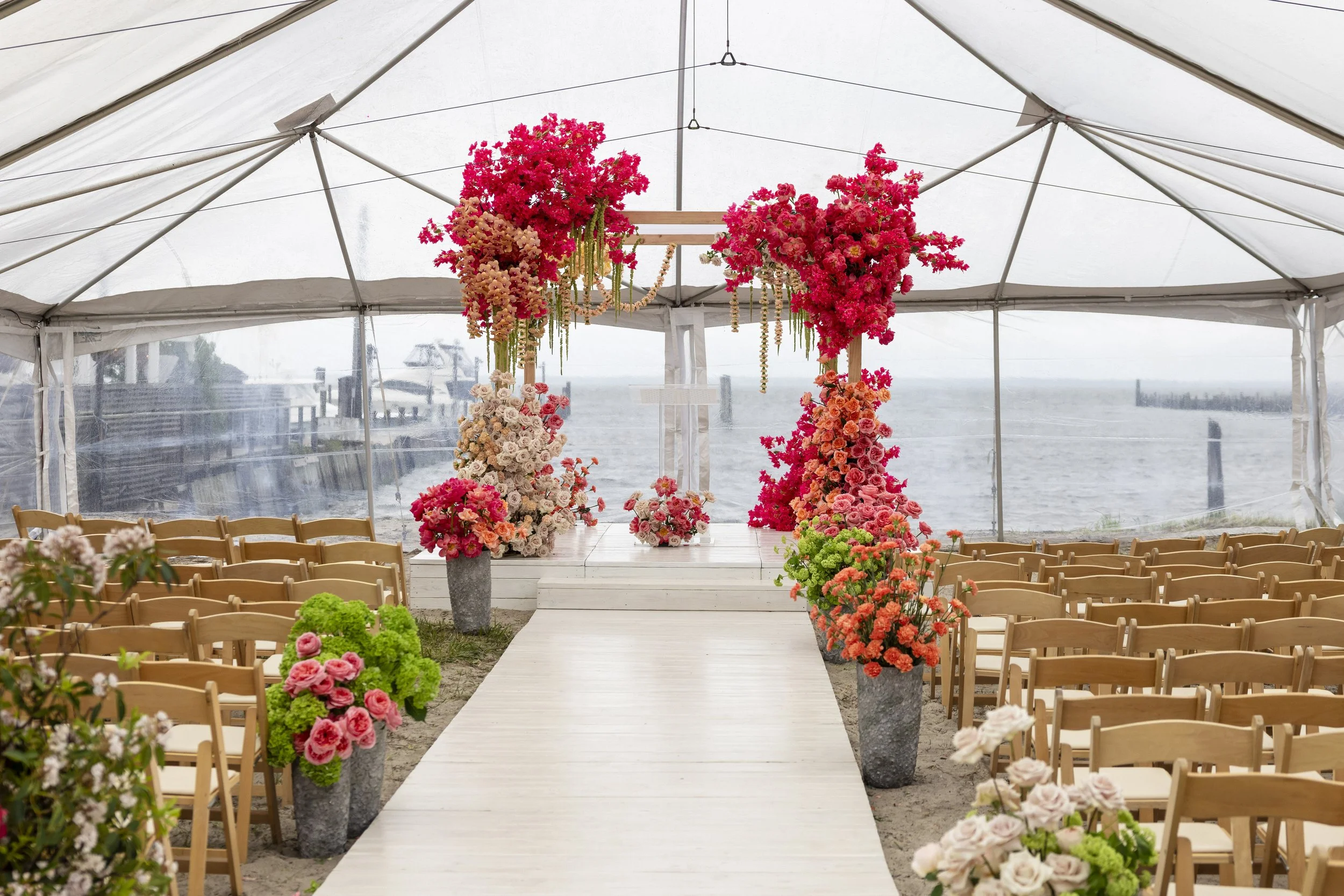 Underwater wedding ceremony setup with chairs, a floral arch, and colorful flowers by the water.
