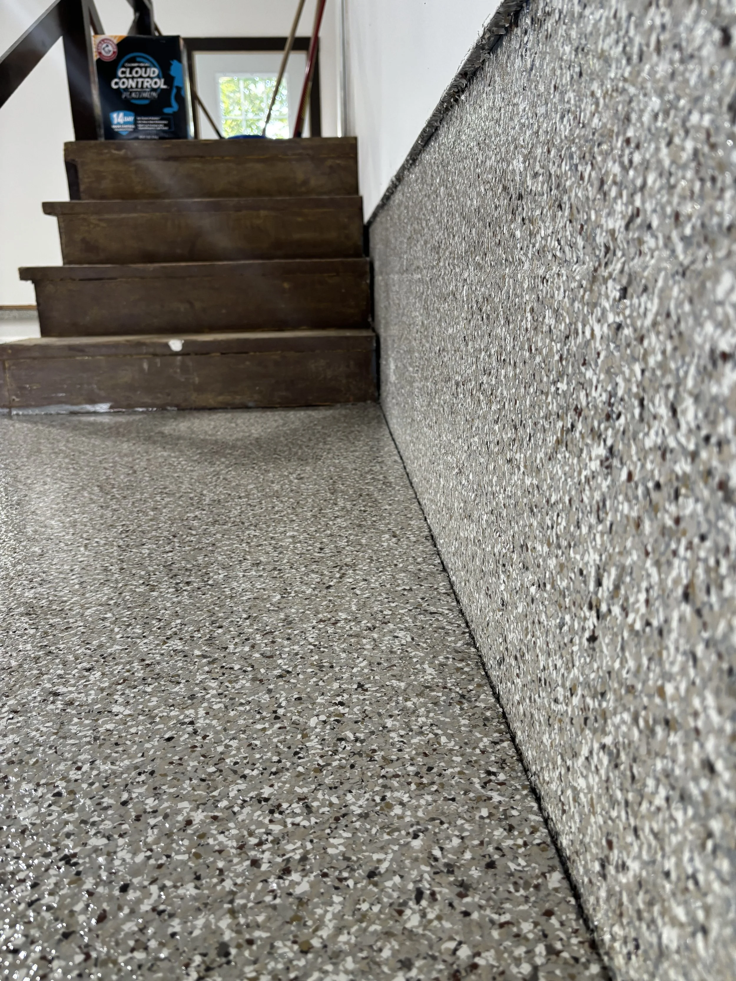 Low-angle shot of a carpeted staircase and textured floor, with a box of cloud control products on top of the stairs near a window.
