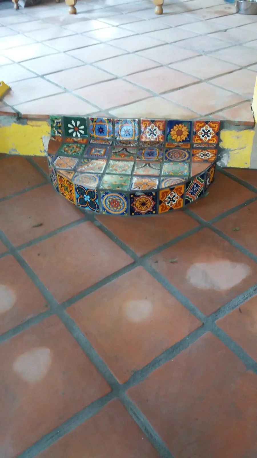 Decorative steps with colorful ceramic tiles at the entrance of a room, showing a tiled flooring pattern.