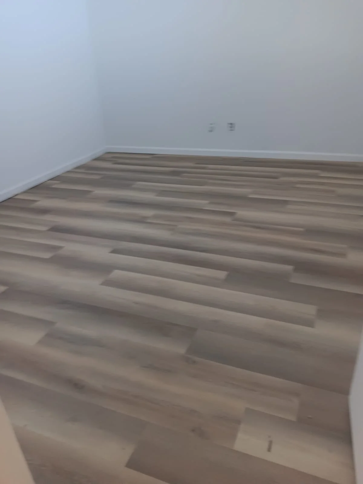 Empty room with white walls and wood-look vinyl flooring.