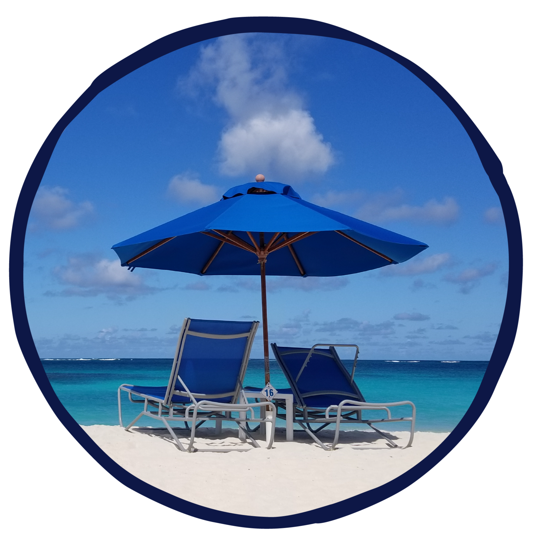 Two blue lounge chairs under a large blue umbrella on a sunny beach with white sand and turquoise water, cloudy sky in the background.