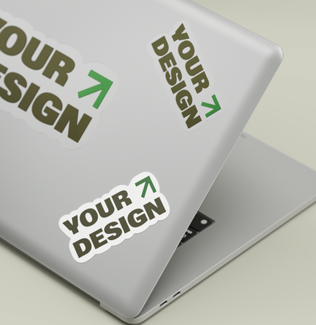 Laptop with stickers that read 'Your Design' with a green arrow, placed on a light-colored surface.