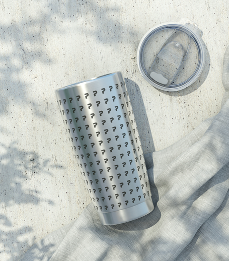 A silver tumbler with black question mark patterns on it and a clear lid with a straw, placed on a light-colored surface with a gray cloth nearby.