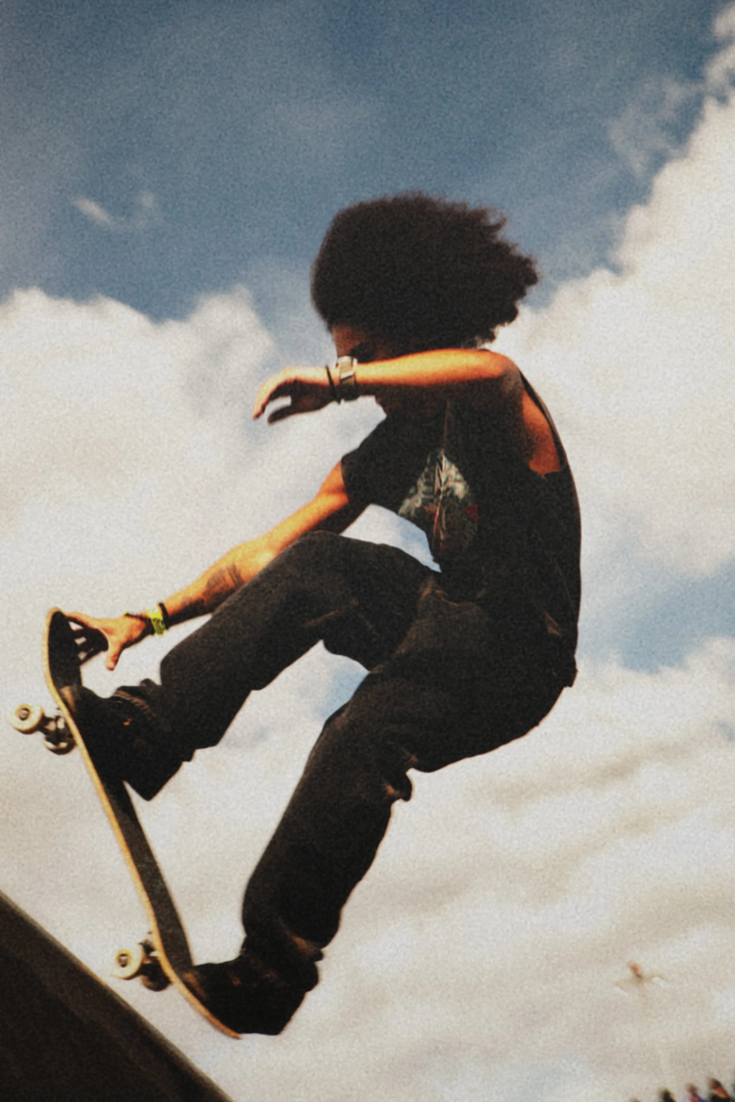 Une personne en skateboard effectuant une figure acrobatique contre un ciel nuageux.