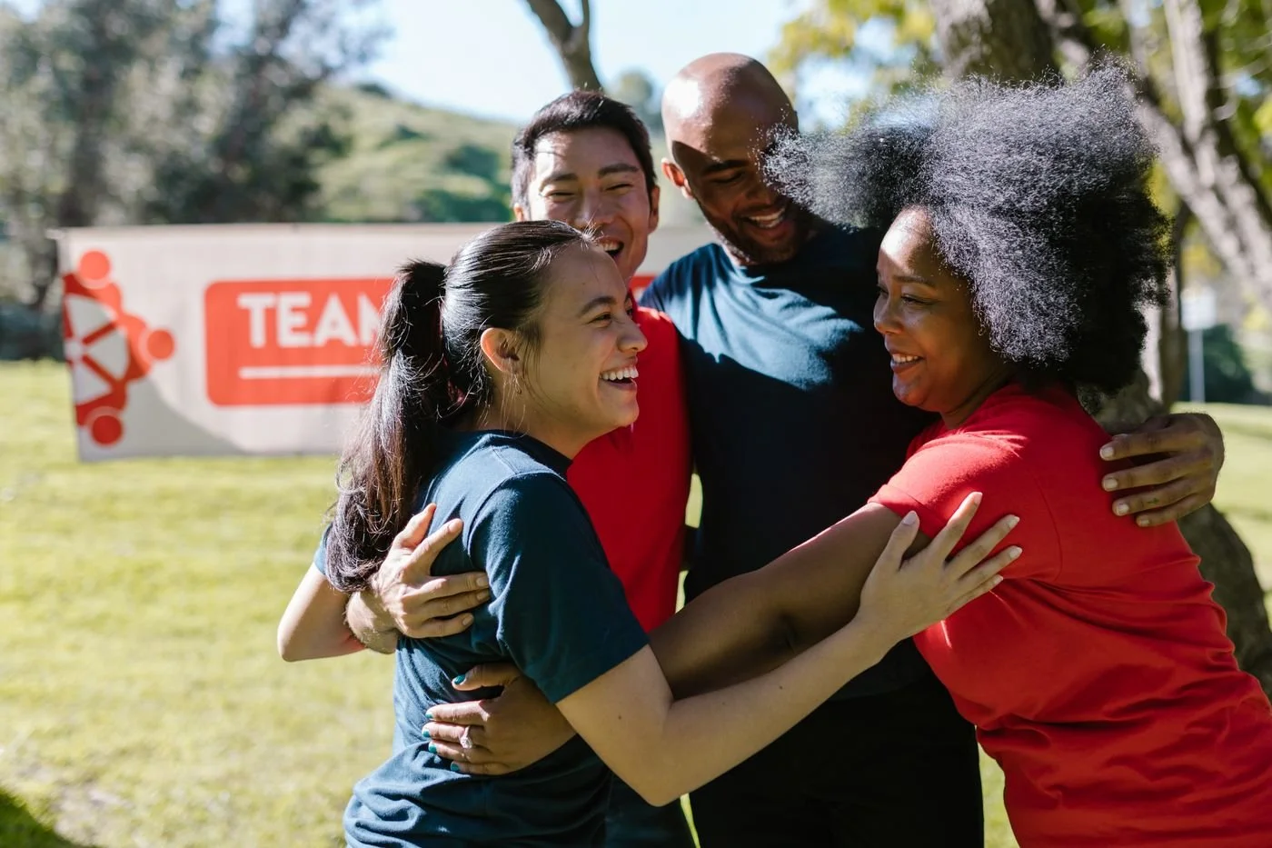 A diverse team of colleagues sharing a joyful group hug outdoors, celebrating teamwork and collaboration.