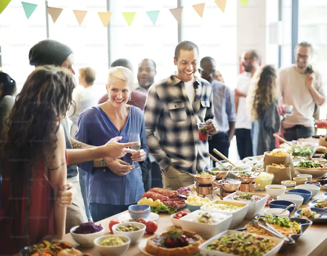 A diverse group of people sharing food and conversation at a community gathering, celebrating connection, inclusion and togetherness.