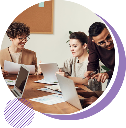 A diverse team of colleagues collaborating around a table with laptops, documents and a tablet, representing teamwork, shared ideas and human-centred innovation.
