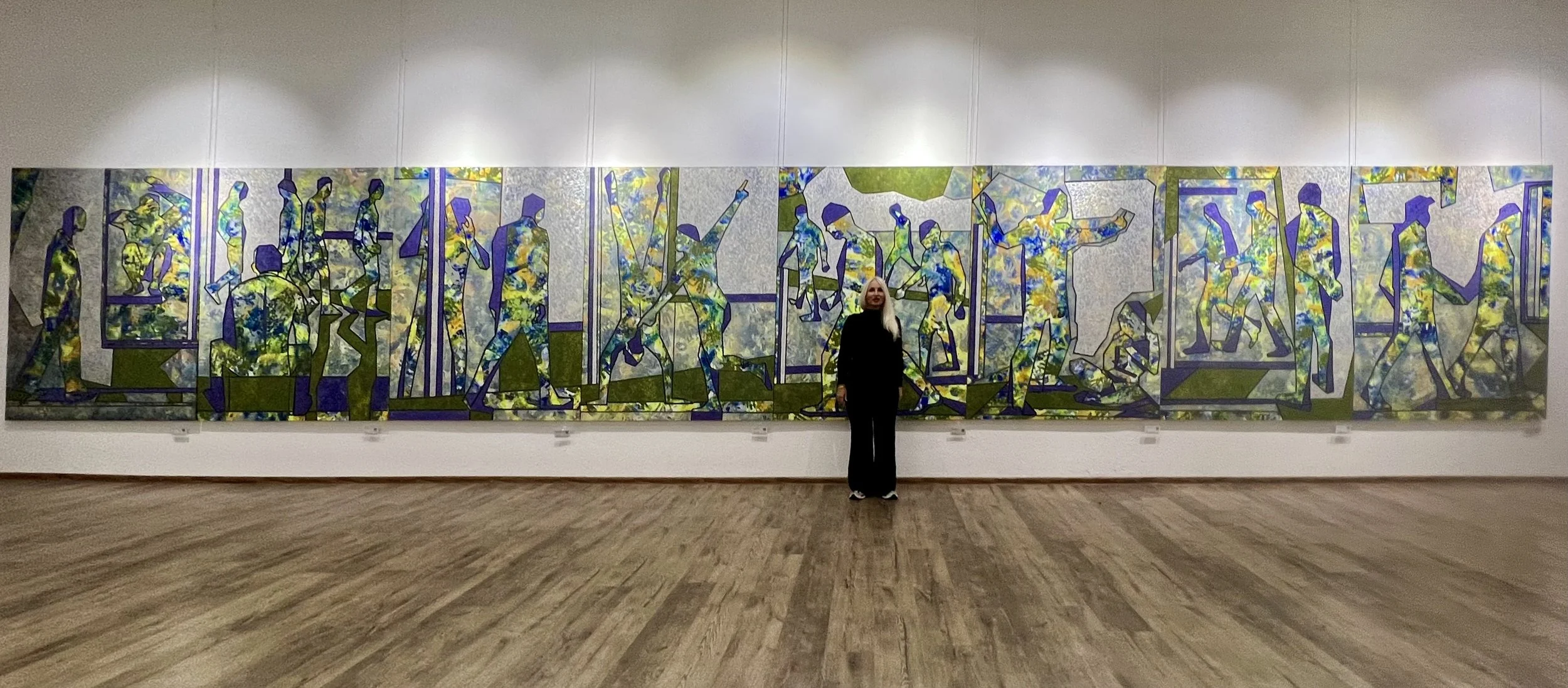 Iryna Sushelnytska standing before the nine-panel installation Nine | Human Structure.