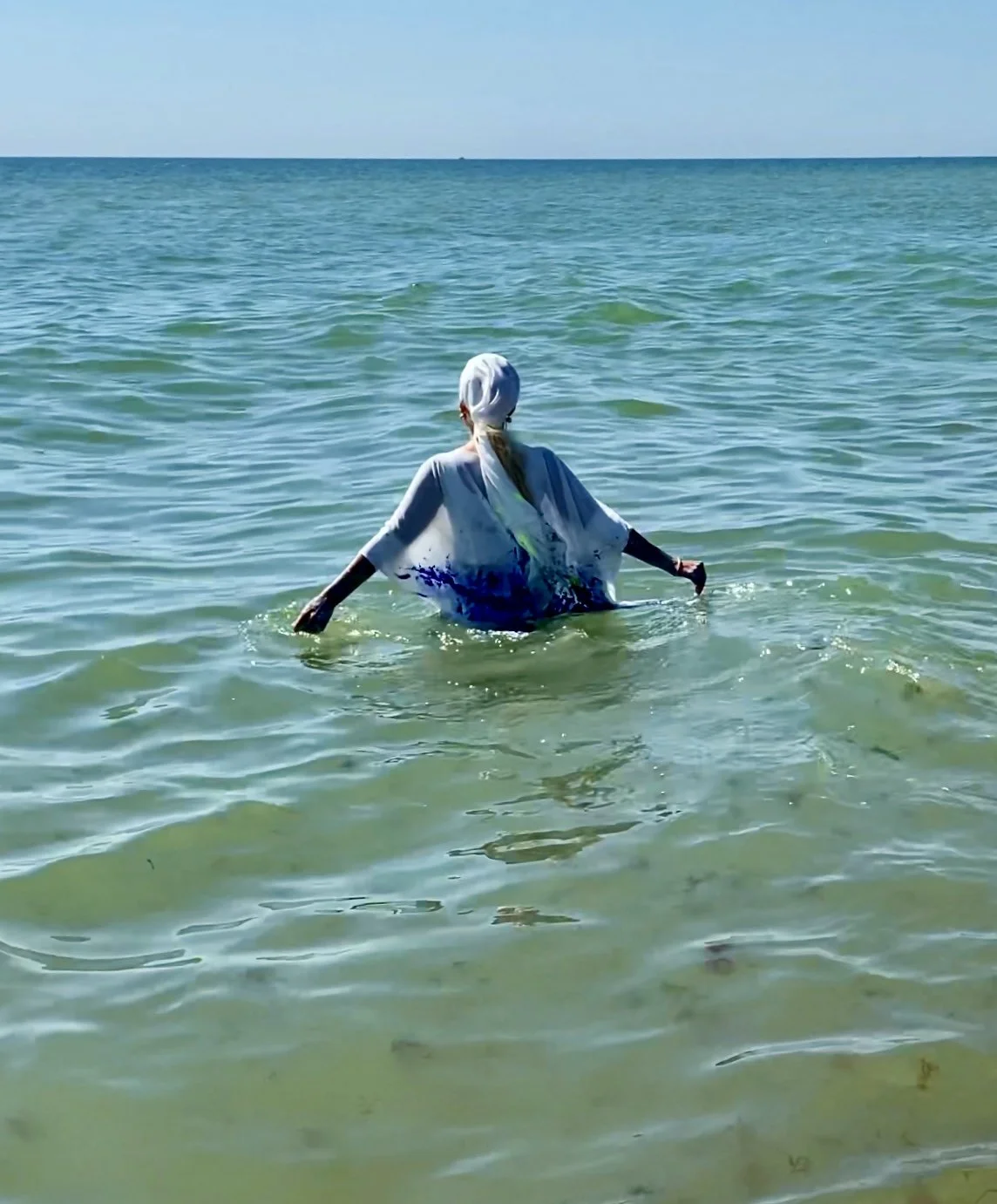 Iryna Sushelnytska entering the sea in paint-marked white clothing at the conclusion of the Nine performance.
