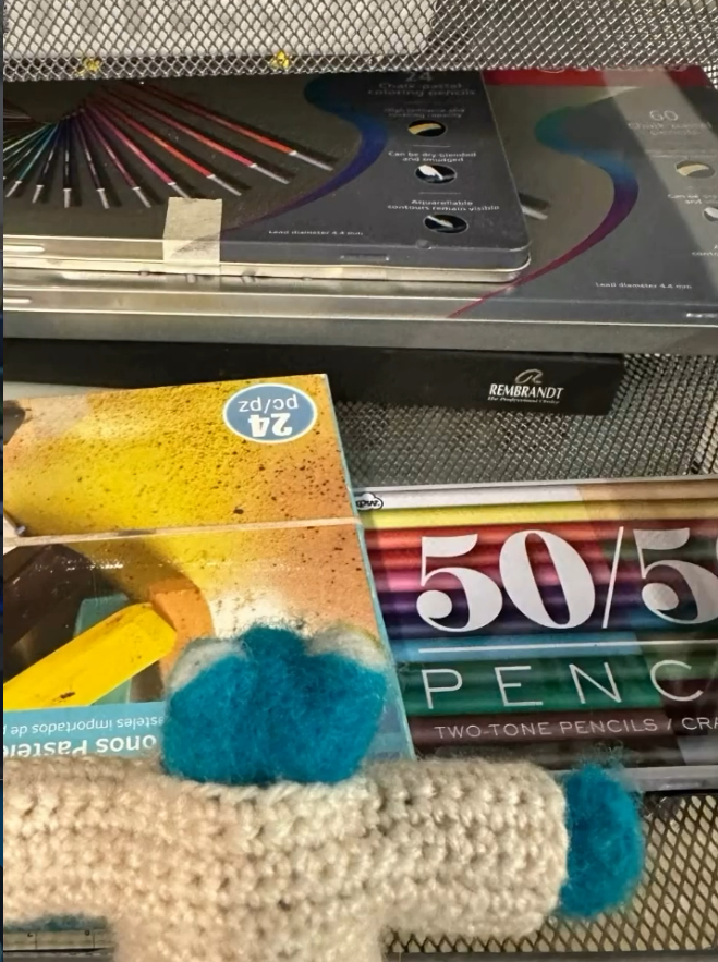 A set of colored pencils and 50/50 penny art supplies on a shopping cart.