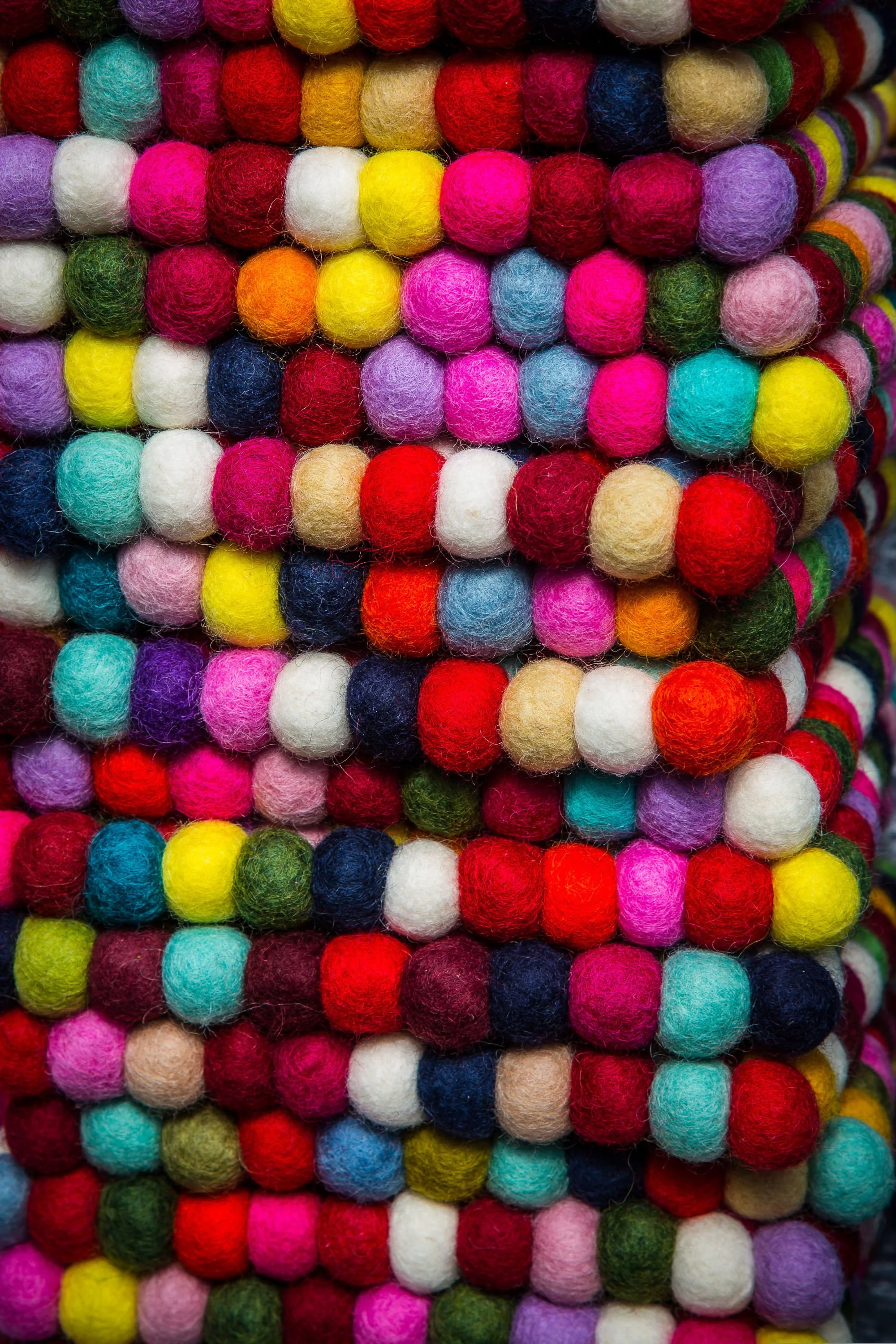 Close-up view of stacked multicolored felted wool balls.