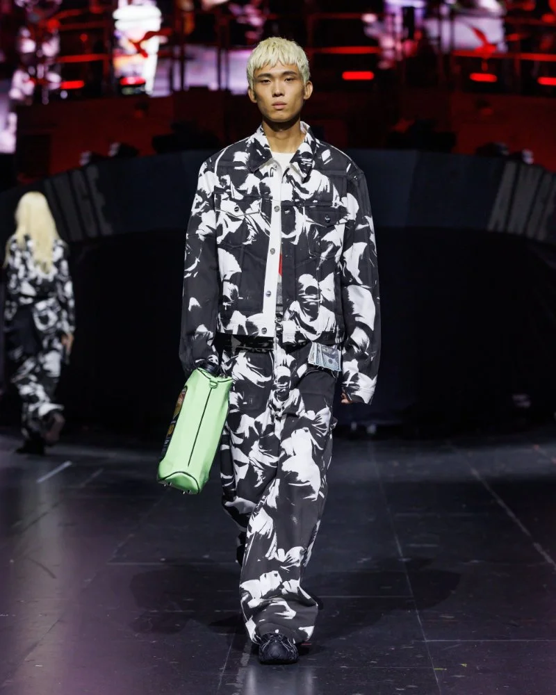 Ensemble ample couvert d’un imprimé photographique noir et blanc, porté avec une mallette vert clair, défilé AWGE SS27.