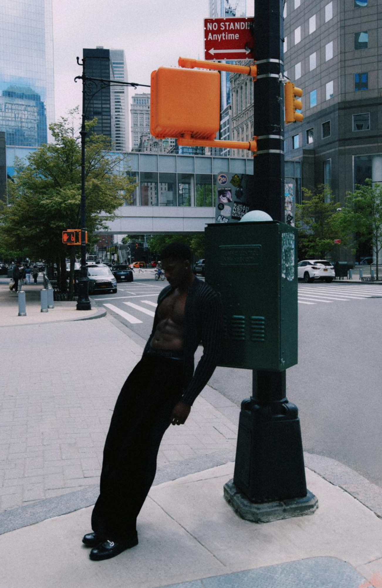Diptyque urbain d’Akosa dans les rues de New York, portant un cardigan sombre ouvert sur le torse et un pantalon noir, photographié en couleur puis en noir et blanc.