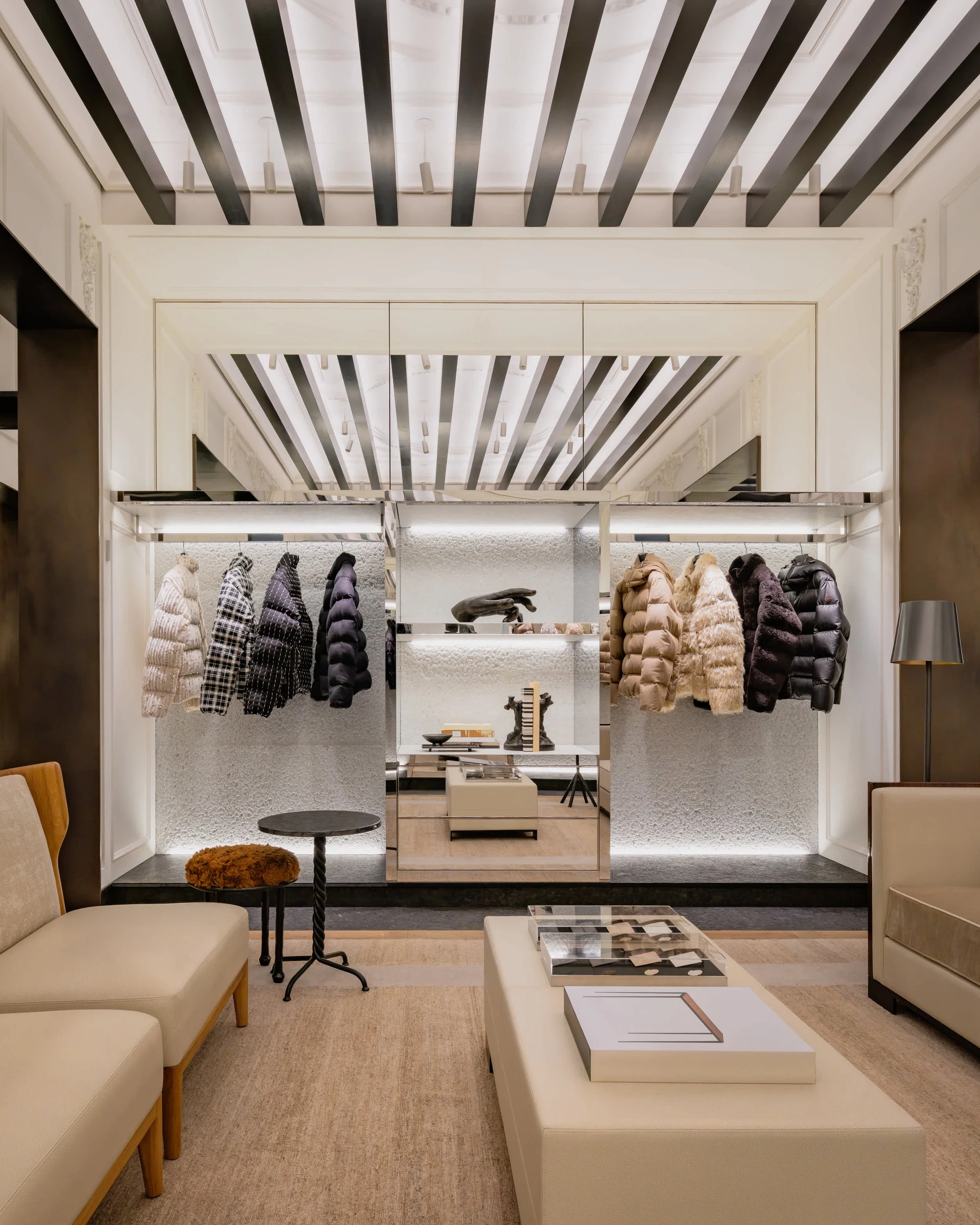 Espace aux tons clairs dans Moncler Fifth Avenue, avec des assises beiges et des vêtements présentés au fond.