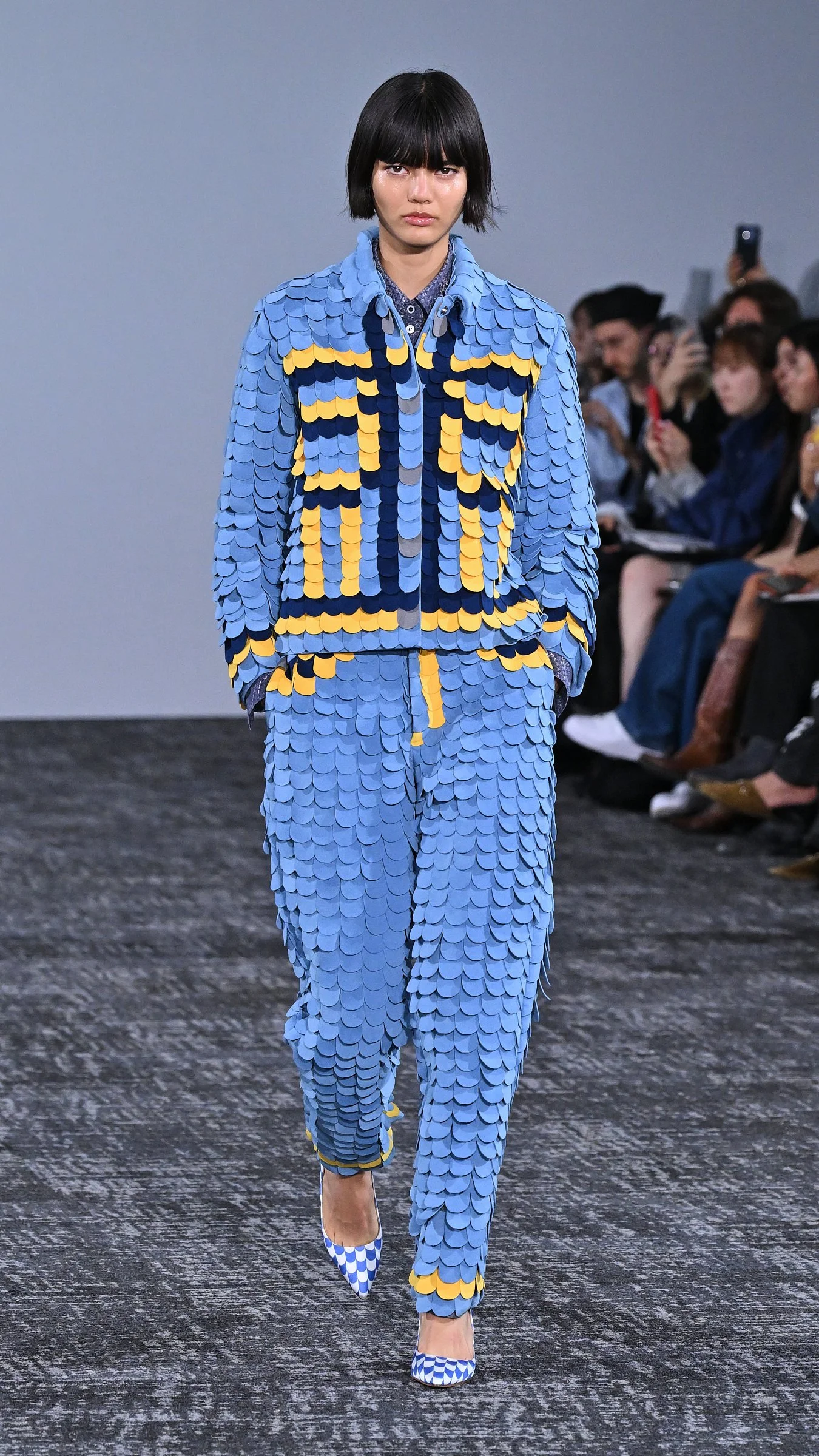Mannequin en combinaison ajustée turquoise sur le podium du défilé Anrealage printemps-été 2027 à Paris.