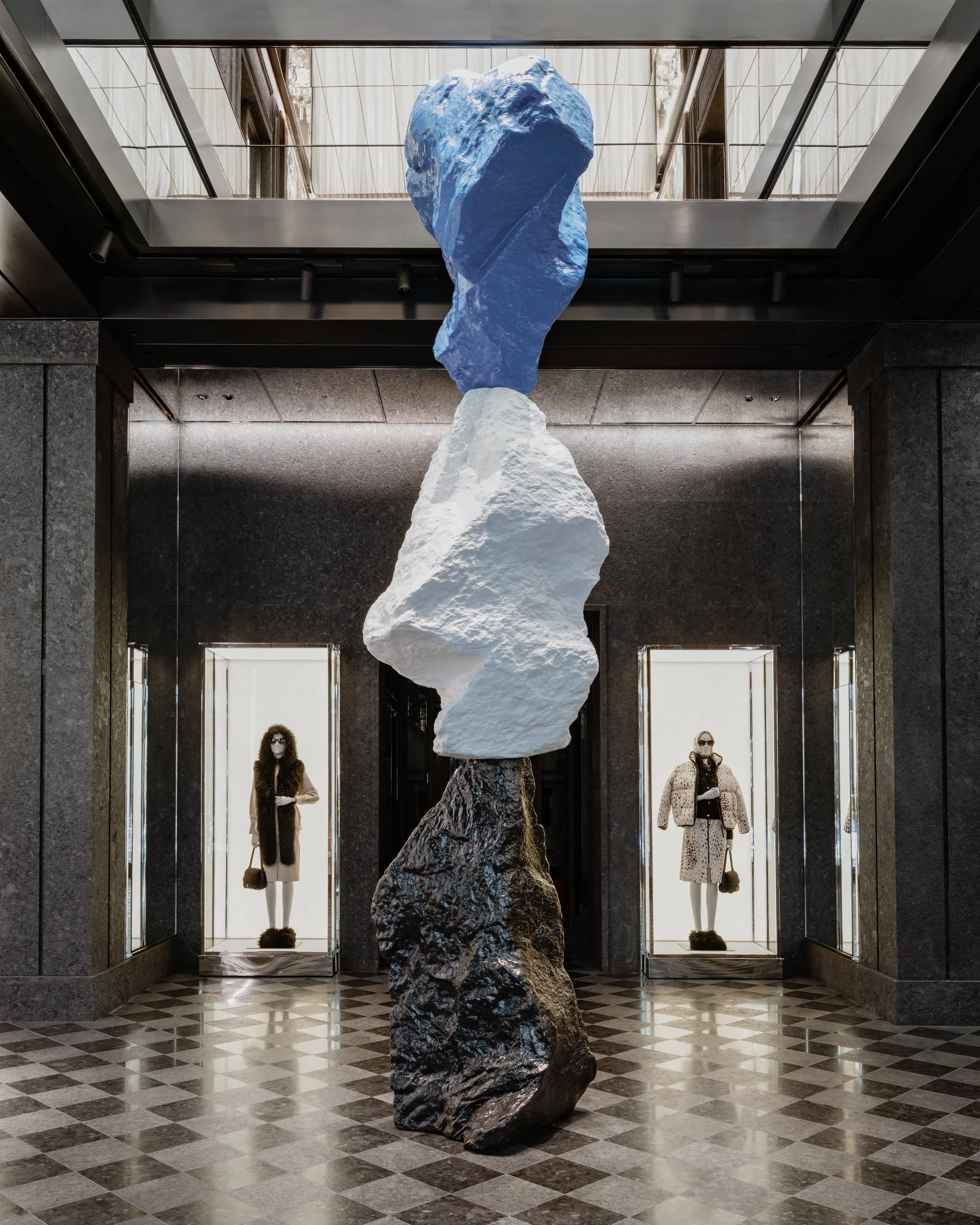 Sculpture composée de volumes clairs superposés au centre de la boutique Moncler Fifth Avenue, au-dessus du sol à damier.