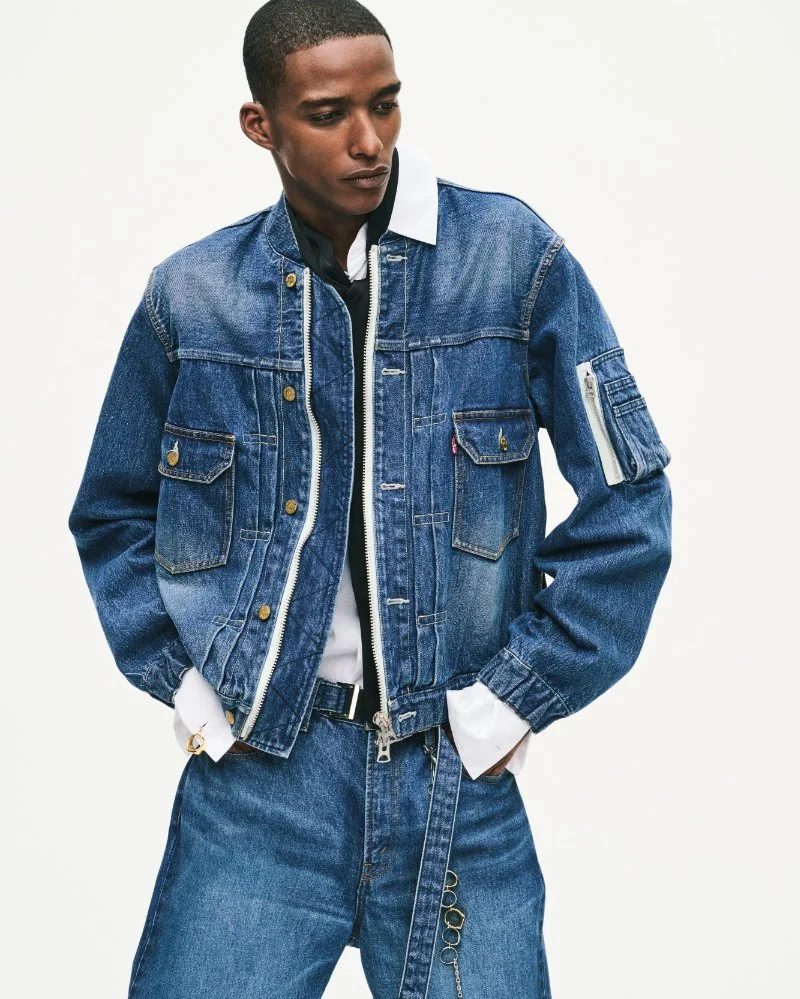 Mannequin en blouson Levi’s x sacai en denim bleu délavé, avec poche sur la manche, mains dans les poches, sur fond clair.