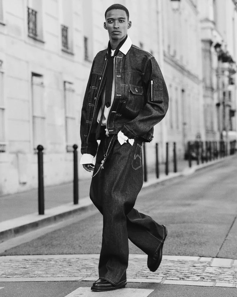 Mannequin marchant dans une rue en ensemble denim sombre Levi’s x sacai, sur une photographie en noir et blanc.