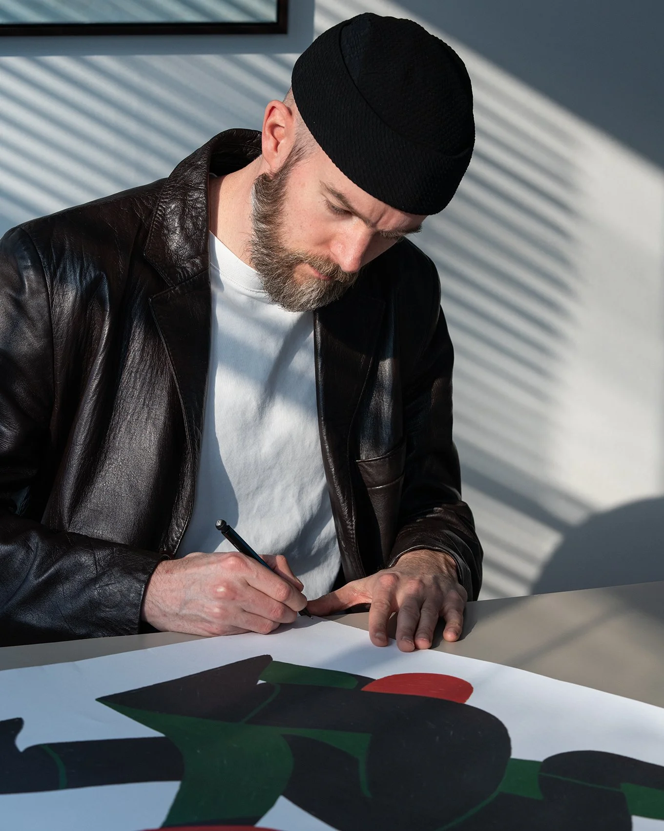 L’illustrateur Timo Kuilder assis et présentant un tirage géométrique coloré.