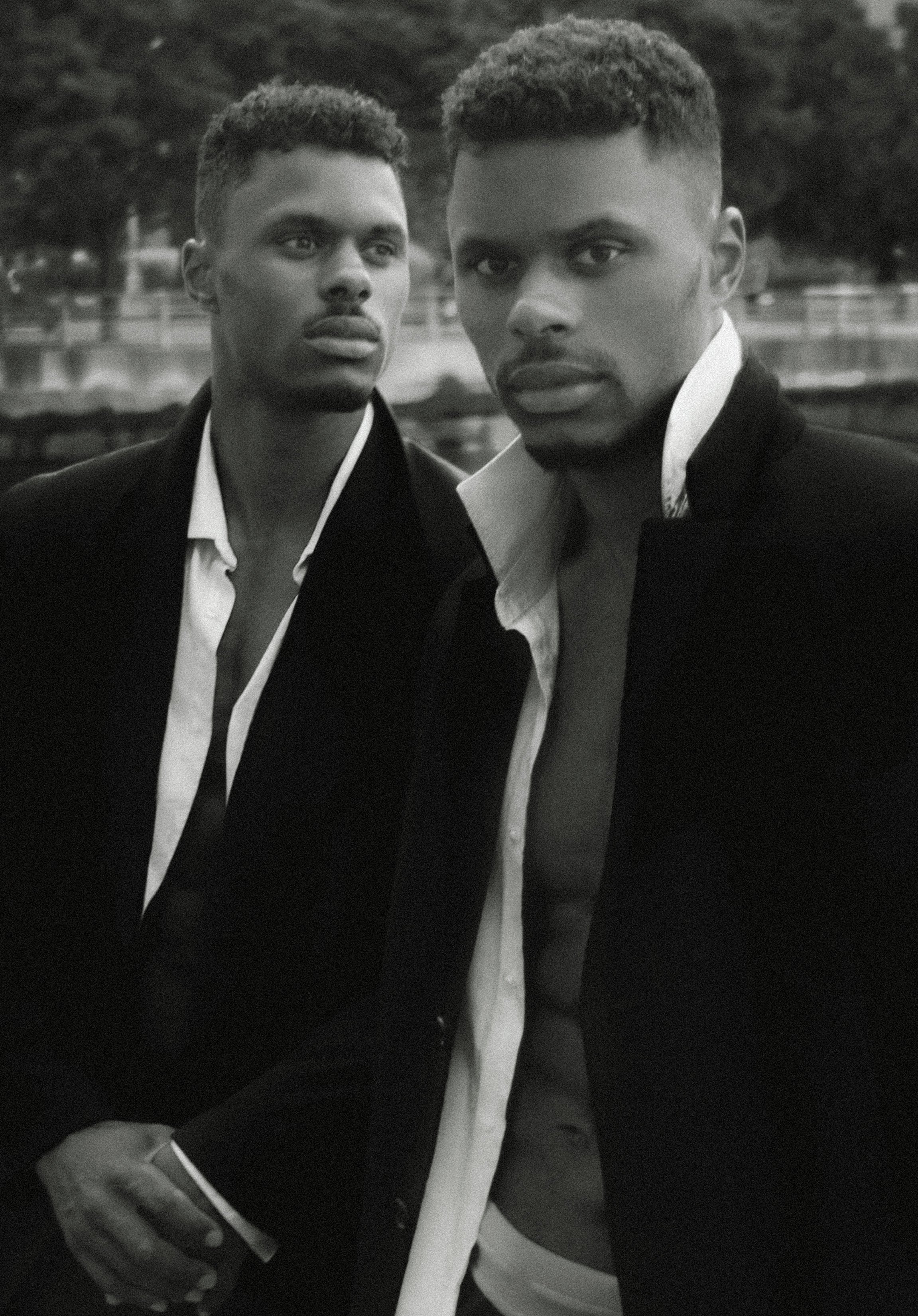Charles et Maxence Bertimon en vestes sombres et chemises claires, photographiés en noir et blanc dans un décor urbain.