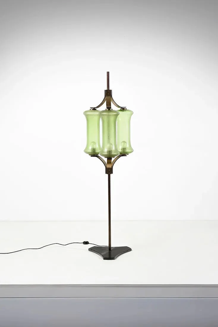 A vintage-style floor lamp with a green glass shade and a metal stand against a plain white background.