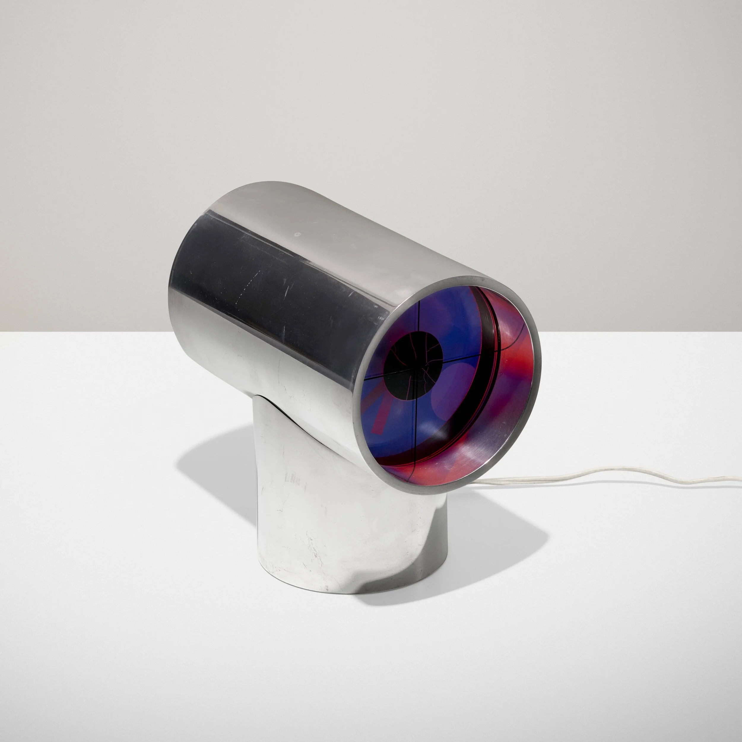 A cylindrical object with a silver body, a black top, a red and blue circular design on one end, and a white cord attached at the bottom, placed on a white surface against a plain white background.