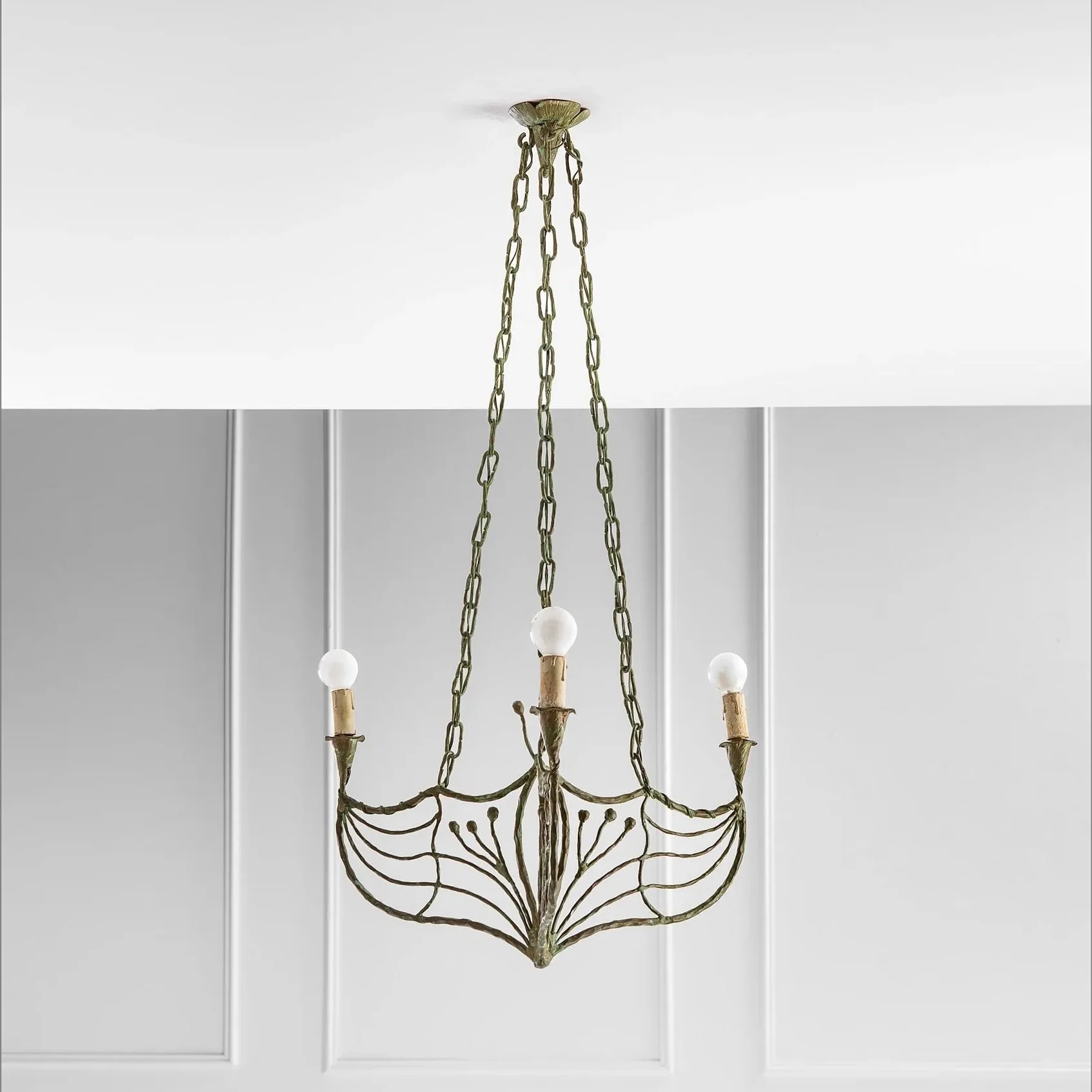 A chandelier with a metal frame designed like a flower, hanging from a chain attached to a white ceiling.