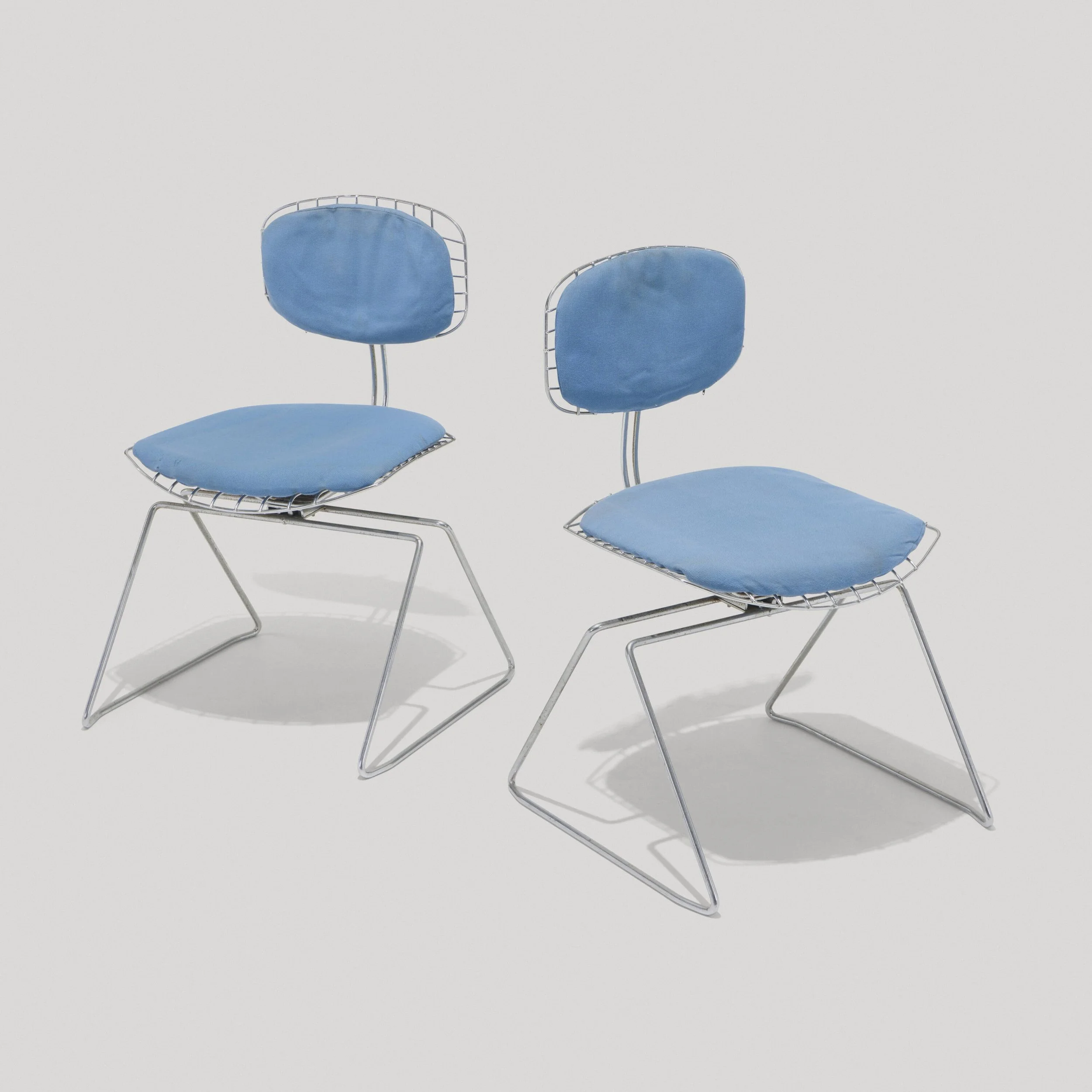 Two modern blue chairs with metal frames and cushioned seats and backs are against a plain white background.