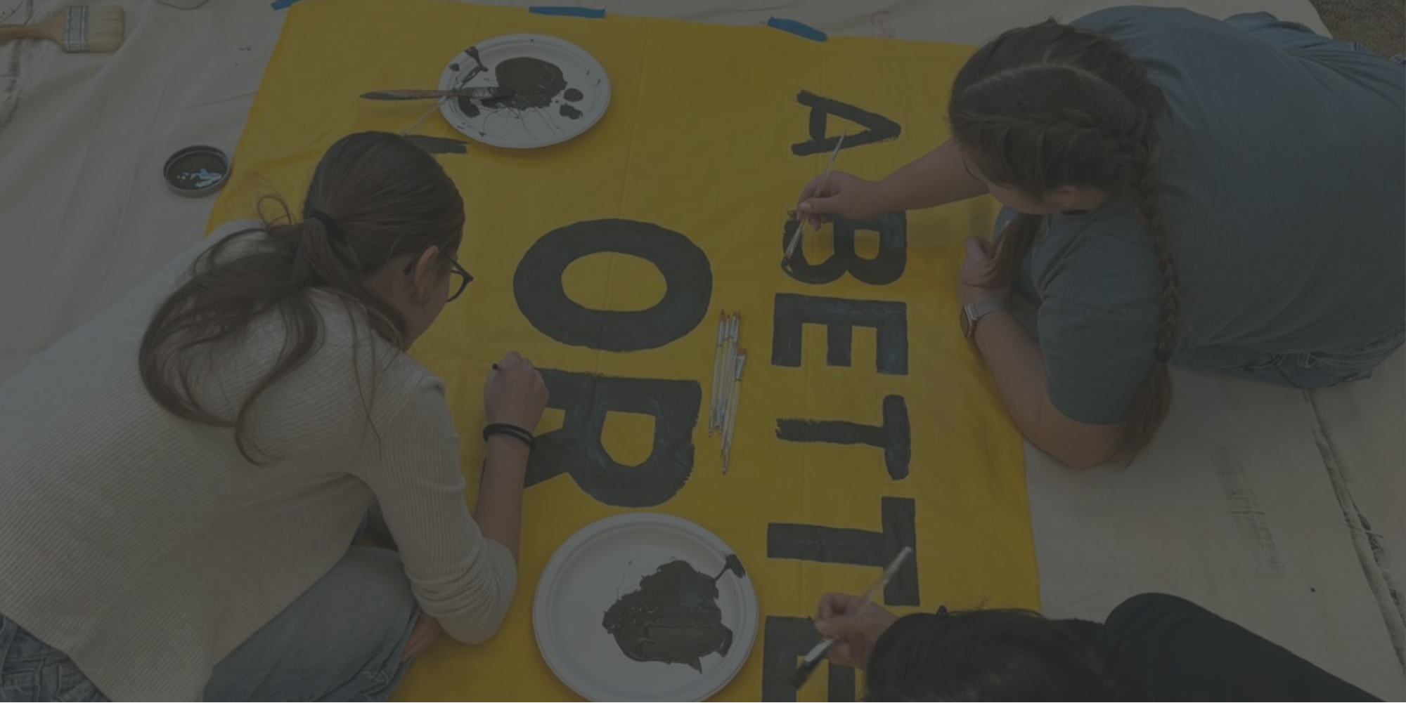 Sunrise members paint a sign during an art build