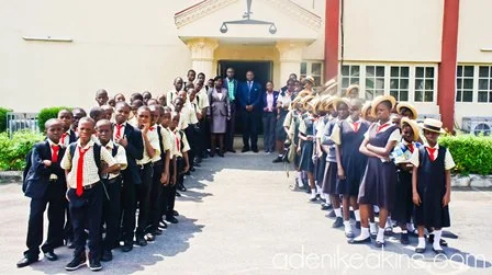 Students in school uniforms and teachers standing outside school entrance