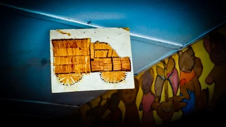 A box with stacked firewood and a paper with a drawing of a wagon or cart on top.