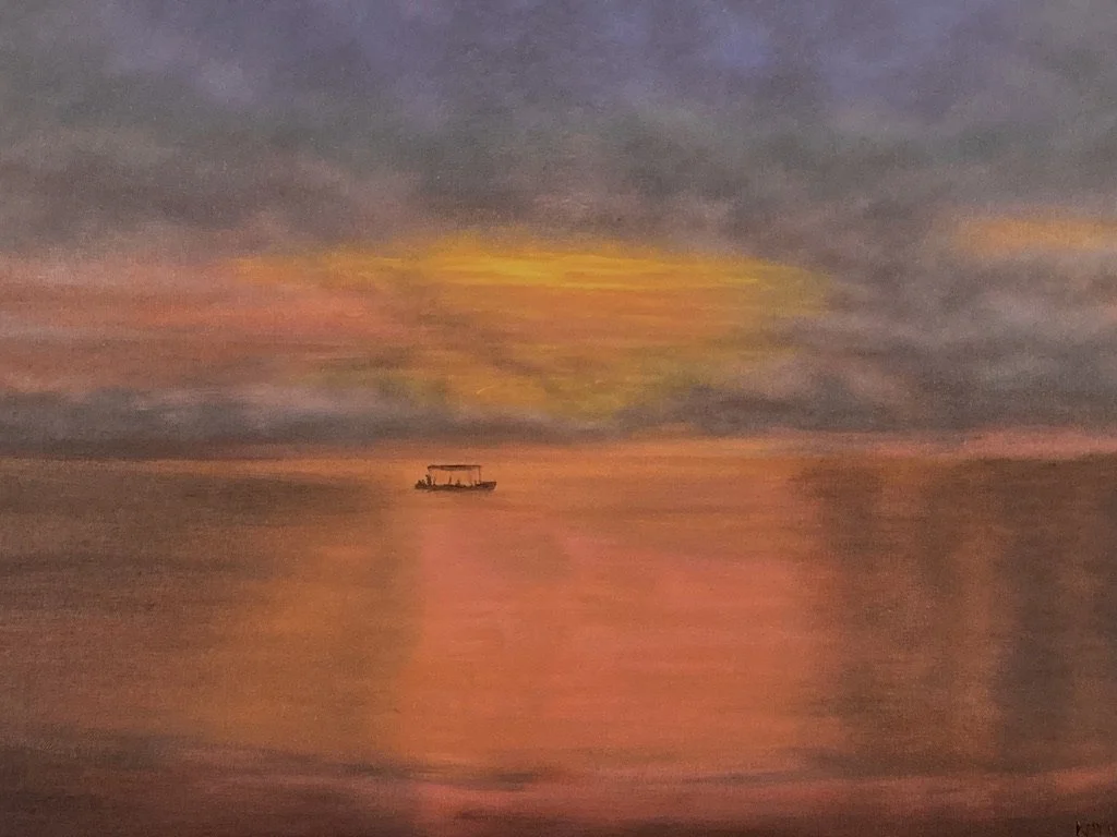 A colorful sunset reflecting on the ocean with a boat in the distance.