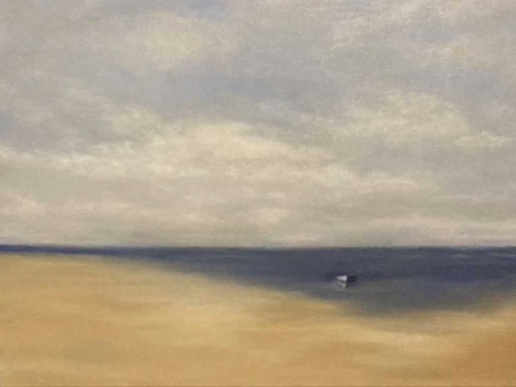 A seascape with a vast beach and small boat at low tide under a blue and white sky.