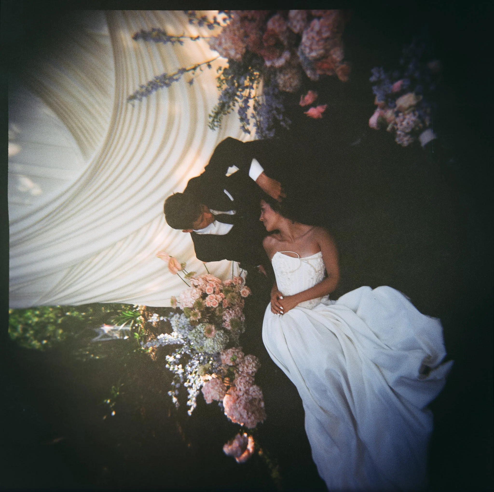 Editorial wedding portrait featuring a trending draped fabric backdrop, garden florals, and romantic newlywed moments.