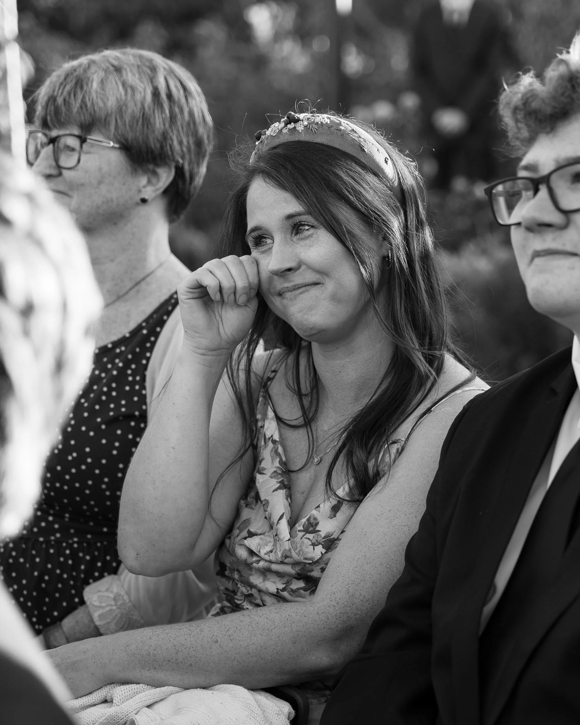 Wedding guest wiping away tears during wedding ceremony