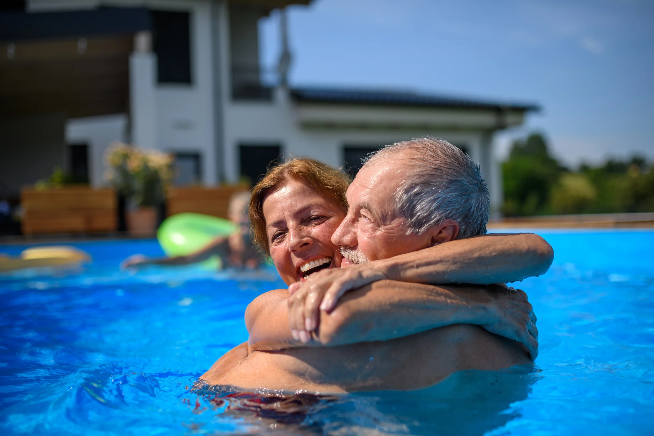 happy couple enjoying clear backyard pool Claremont CA after professional pool cleaning service