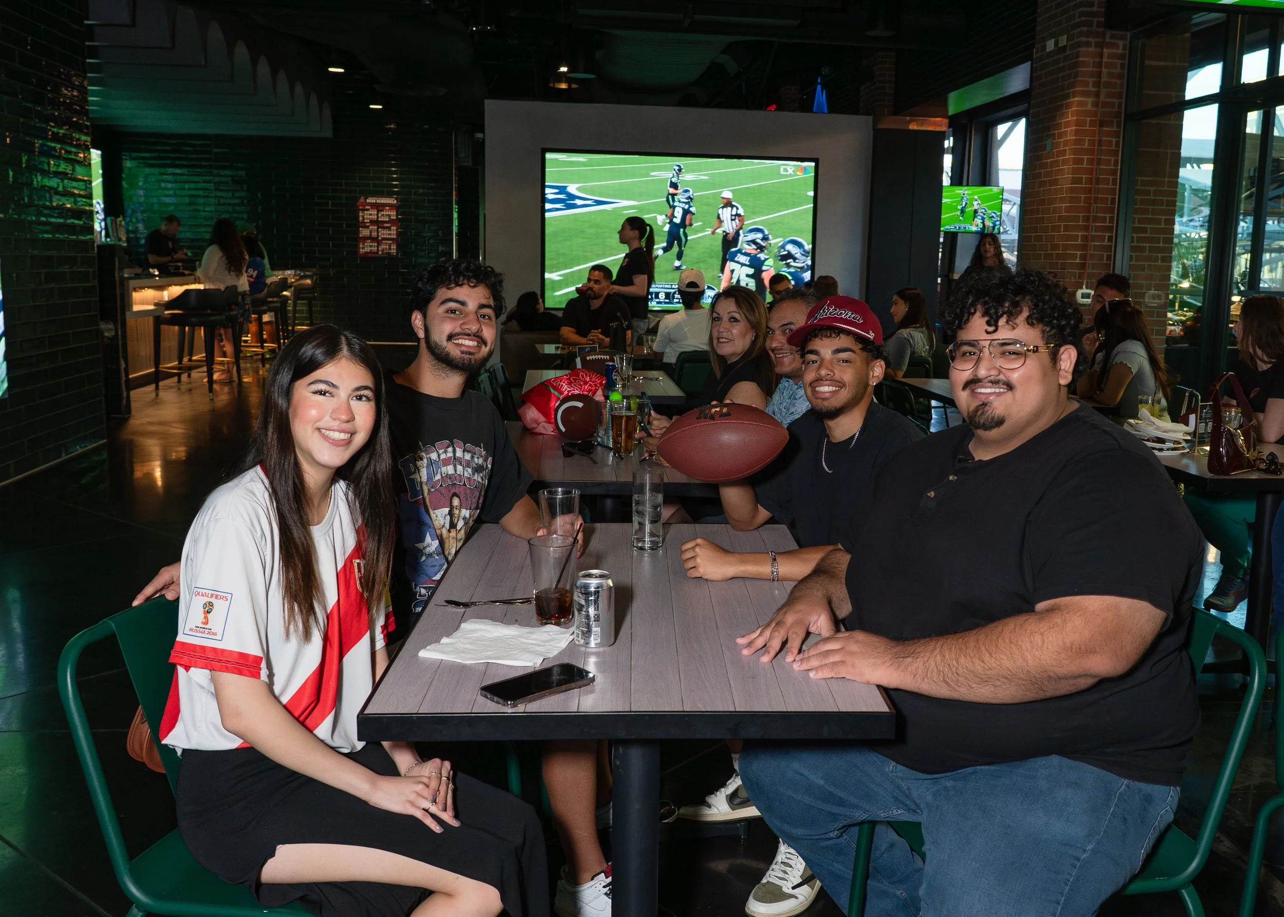 Group of people watching a football game at a restaurant or bar.