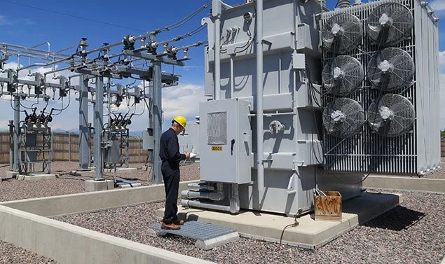 Técnico de mantenimiento inspeccionando un transformador eléctrico en una subestación.